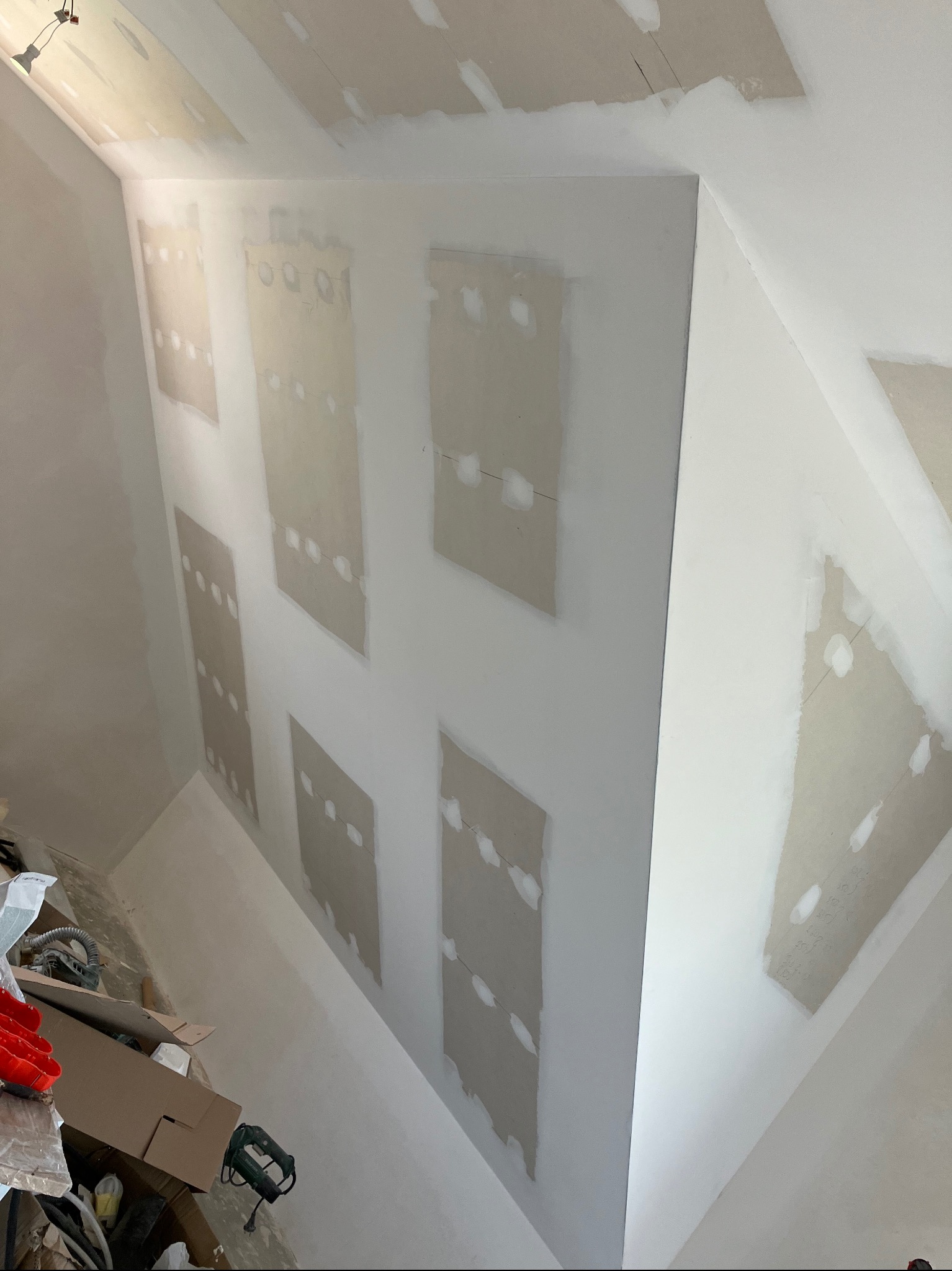 Sufit i ściany poddasza po montażu płyt gipsowo-kartonowych, widoczne miejsca szpachlowania łączeń i wkrętów, na podłodze widoczny bałagan po pracach.