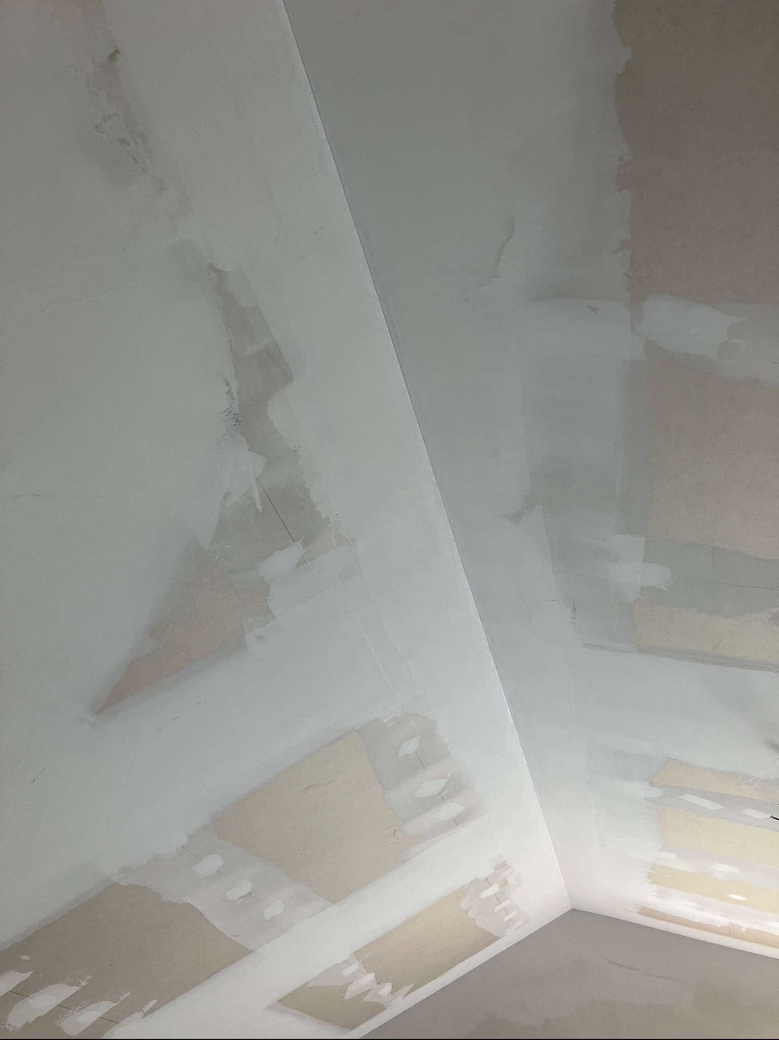 Niedokończone szpachlowanie sufitu i ścian, widoczne fragmenty oryginalnej powierzchni oraz nałożona biała masa szpachlowa, oświetlenie dzienne.