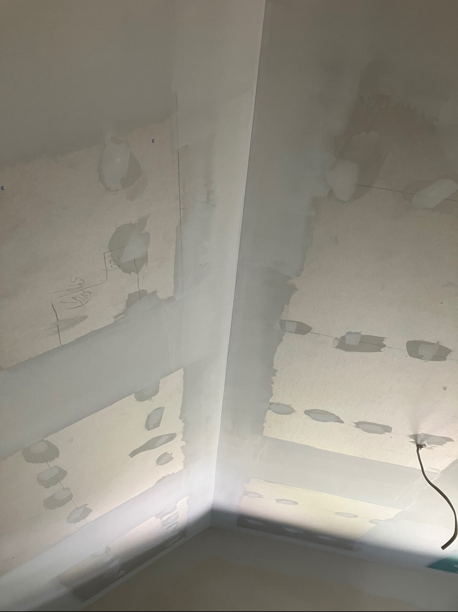 Wnętrze w Jastrzębi k. Tarnowa w trakcie prac przygotowawczych do malowania: ściany i sufit po szpachlowaniu, widoczne ślady po łataniu ubytków i zarys instalacji elektrycznej.