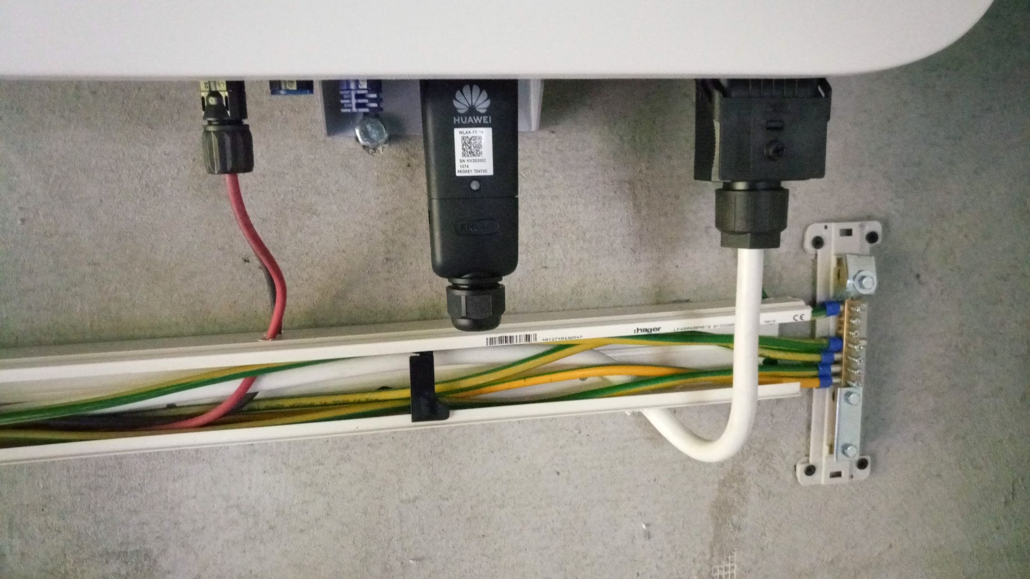 Szczegółowe ujęcie instalacji elektrycznej modułu komunikacyjnego Huawei w systemie fotowoltaicznym, z widocznymi przewodami w białej listwie montażowej i elementami złącznymi.