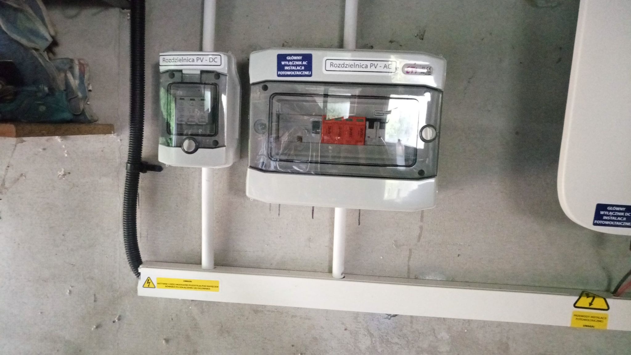 Rozdzielnice PV-DC i PV-AC zamontowane na ścianie w Rzeszowie, widoczne oznaczenia ostrzegawcze i główne wyłączniki instalacji fotowoltaicznej.
