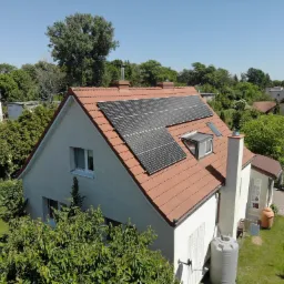 Instalacja paneli słonecznych na dachu domu jednorodzinnego w Inowrocławiu, widok z góry, z widocznym zbiornikiem na deszczówkę w ogrodzie.