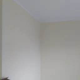 Pomieszczenie po malowaniu ścian na kremowo, widoczny fragment szafki w lewym dolnym rogu i biały pasek dekoracyjny pod sufitem.