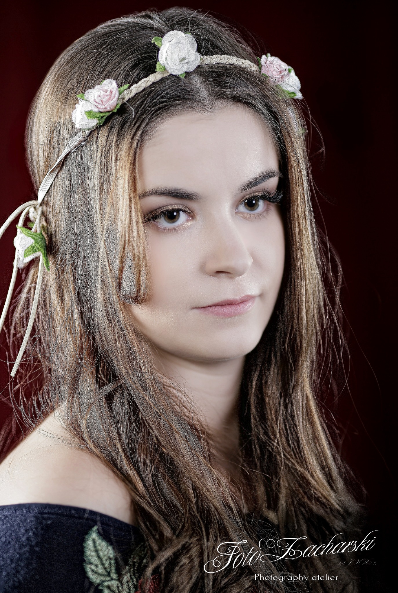 Portret młodej kobiety z wiankiem z białych i różowych kwiatów na brązowych włosach, na ciemnoczerwonym tle.