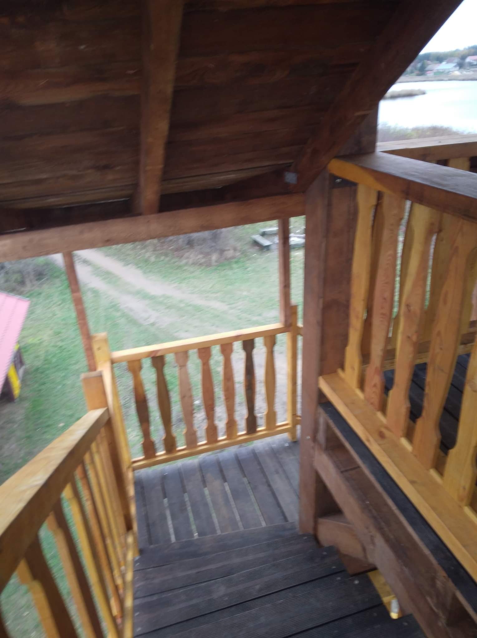 Drewniana konstrukcja z balustradą, widok z góry na schody i otoczenie z jeziorem w tle.