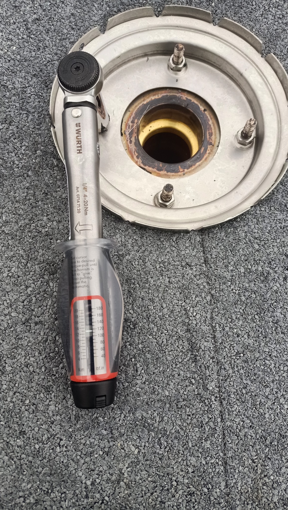 Klucz dynamometryczny marki Wurth leżący na szarym dachu z papy bitumicznej obok metalowego elementu z otworami na śruby.