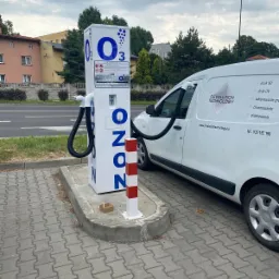 Stanowisko do ozonowania pojazdów z podłączonym wężem do wnętrza białego samochodu dostawczego z logo firmy Revolution Technology na tle ulicy.