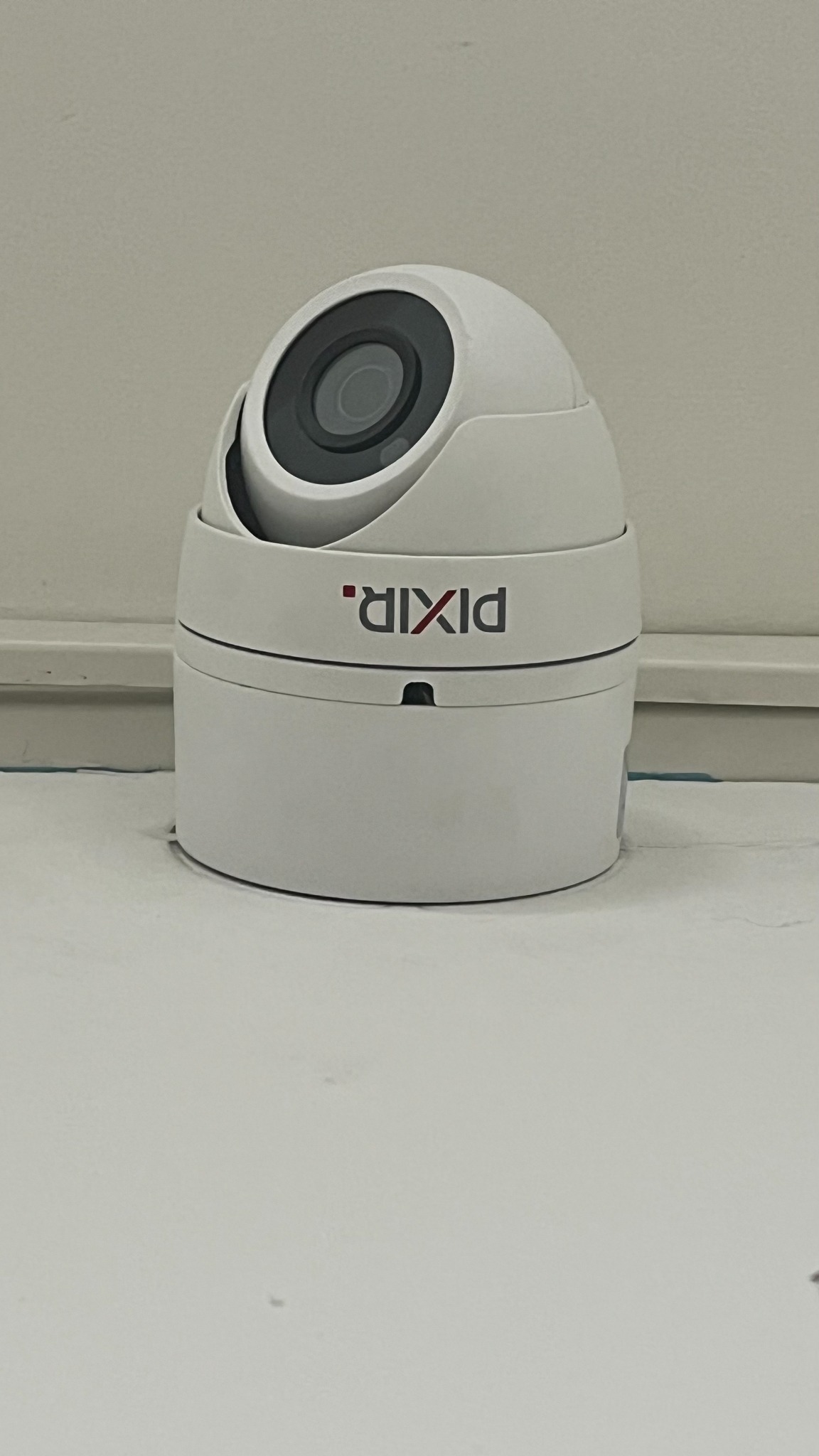 Kamera monitoringu kopułkowa marki PIXIR, umieszczona na białej powierzchni, z widocznym obiektywem i logo firmy.
