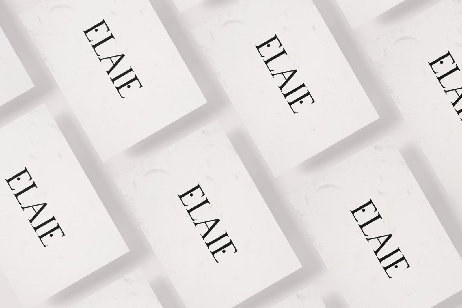 Układ wizytówek z nazwą 'ELAIE' w eleganckiej czcionce na tle o subtelnej teksturze papieru.