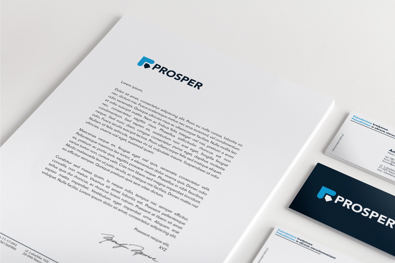 Papier firmowy z niebieskim logo i tekstem Lorem Ipsum, wizytówki z logo firmy na białym tle, minimalistyczny design.