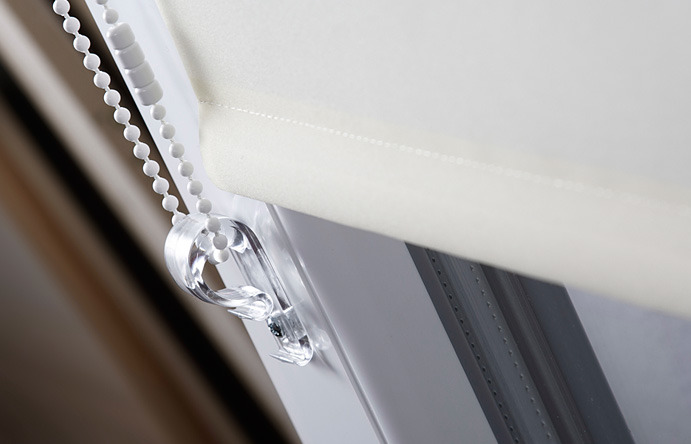 Detal widoku rolety okiennej z łańcuszkiem kulkowym i przezroczystym uchwytem, widoczny mechanizm montażowy.