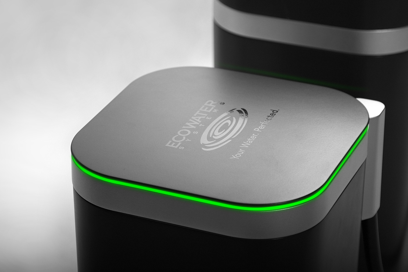 Zbliżenie na górną część czarnego filtra do wody z podświetleniem LED i logo EcoWater Systems.