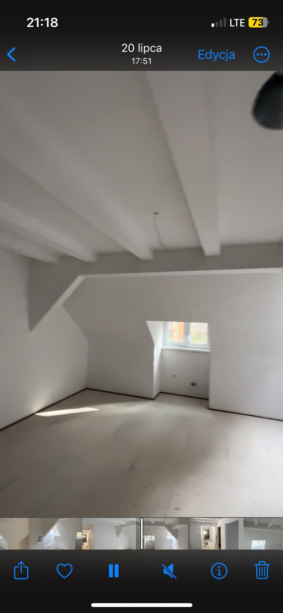 Poddasze po remoncie, świeżo pomalowane na biało, widoczne belki stropowe, okno dachowe i surowa podłoga przed wykończeniem.