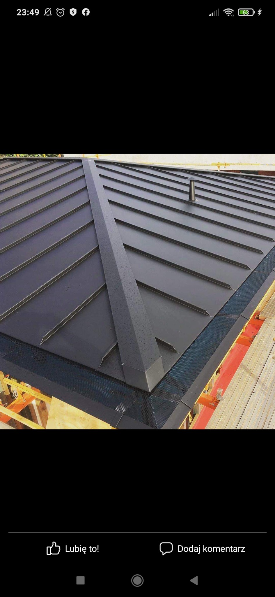 Nowoczesne, grafitowe pokrycie dachowe z metalu, widok z góry na fragment dachu z rynnami zabezpieczonymi siatką w Zgierzu, widoczny kominek wentylacyjny.