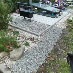 Wykończone miejsce pochówku z granitu, z ławką, ścieżką wysypaną drobnym grysem i obrzeżami betonowymi.