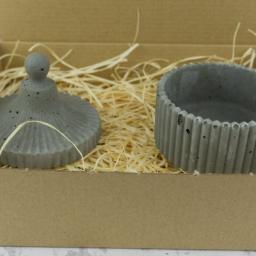 Rausch Beton - Dekoracyjny, betonowy pojemnik z pokrywką w kartonowym pudełku wypełnionym siankiem, prezentowany przez firmę z Gorzowa Wielkopolskiego.