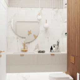 Nowoczesna łazienka w jasnych barwach z marmurowymi płytkami, okrągłym lustrem z dekoracją ptaka, podwieszaną szafką z ryflowanym frontem, złotą armaturą i wiszącą toaletą.