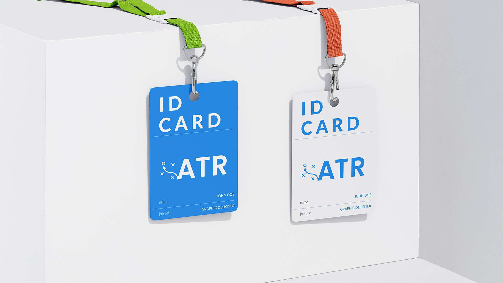 Dwie zawieszone identyfikatory ATR, jeden niebieski z zieloną smyczą, drugi biały z pomarańczową, na białym tle. Widoczne dane: John Doe, Graphic Designer.