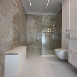 ASK BUD - Elegancka łazienka z marmurowymi płytkami, kabiną prysznicową typu walk-in, podświetleniem LED i białą zabudową meblową z siedziskiem. Minimalistyczny design.