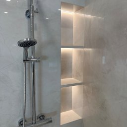 ASK BUD - Wykończona łazienka: chromowana bateria prysznicowa na tle marmurowej ściany z wnęką oświetloną ledami. Minimalistyczny design, nowoczesne wykończenie.