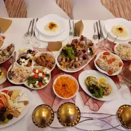 Uroczysty stół cateringowy z różnorodnymi sałatkami, przekąskami i napojami, udekorowany złotymi świecznikami kulistymi, widok z góry.