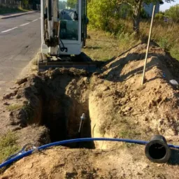 Wykop pod przyłącze wodociągowe fi 32 w Golęczewie, widoczny niebieski rurociąg, wykopany rów i minikoparka.