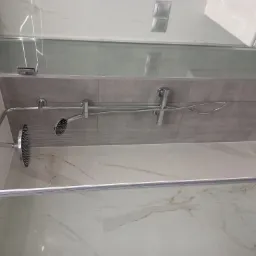 Szklana kabina prysznicowa z deszczownicą i baterią termostatyczną, wykończona płytkami imitującymi marmur i szarymi płytkami na ścianie, widok z góry na wnętrze kabiny.