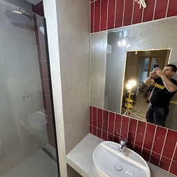 Progress Glazura - Nowoczesna łazienka z kabiną prysznicową typu walk-in, umywalką nablatową i czerwoną glazurą. W lustrze odbija się osoba robiąca zdjęcie.