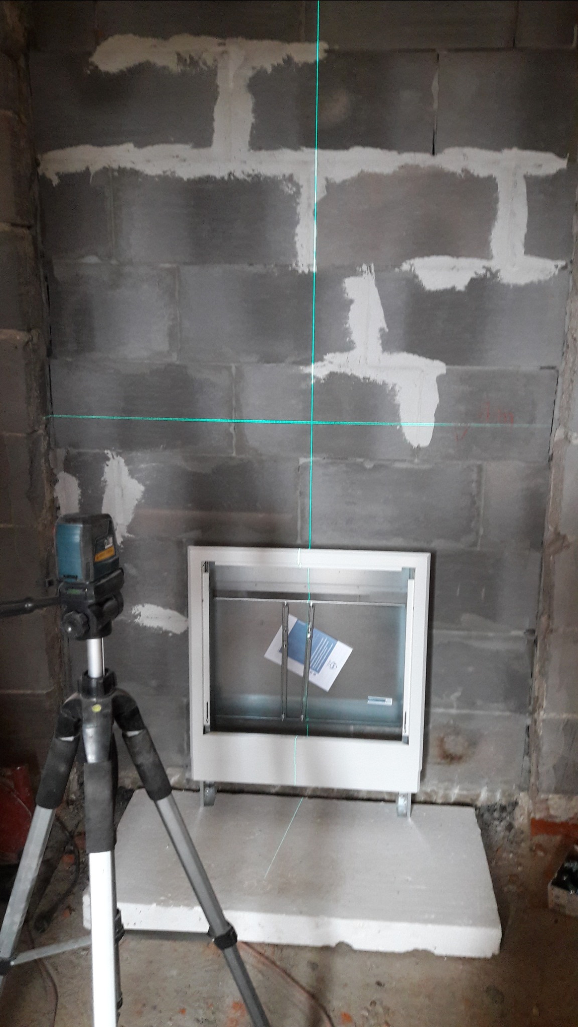 Przygotowanie do montażu wnęki w surowej ścianie z bloków, widoczny laser krzyżowy i poziomowanie wnęki.