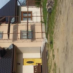 Stanisław Napierała - Dom jednorodzinny w trakcie prac elewacyjnych, widoczne rusztowania, okna zabezpieczone folią, przygotowane do prac wykończeniowych na zewnątrz.