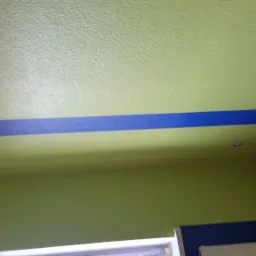 Ściana i sufit pomalowane na zielono z poziomym, niebieskim pasem dekoracyjnym w Żninie. Widoczny fragment ściany wyłożonej boazerią.