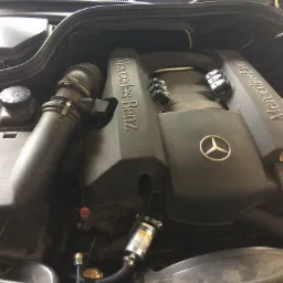 Silnik Mercedes-Benz z widocznym filtrem i instalacją, prawdopodobnie po modyfikacji lub serwisie. Detaliczny widok na komorę silnika z elementami instalacji paliwowej lub gazowej.