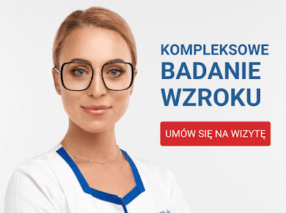 Portret uśmiechniętej kobiety w okularach o grubych, kwadratowych oprawkach, w białym uniformie medycznym z niebieską lamówką, na tle z tekstem 'Kompleksowe badanie wzroku. Umów się na wizytę'.