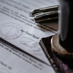 Dokument z pieczęcią, podpisem i długopisem, potwierdzający tłumaczenie na język angielski, widoczny fragment tekstu 'mgr Paweł Bujak'.