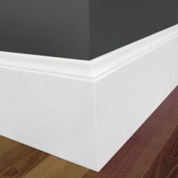 Art-Clean - Szczegółowe ujęcie narożnika ściany pomalowanej na ciemny grafit, z białą listwą przypodłogową o profilowanym kształcie, na tle parkietu z naturalnego drewna.