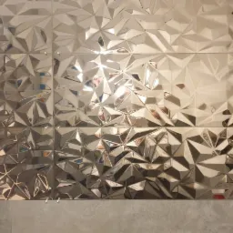 Ściana wyłożona błyszczącymi, metalicznymi płytkami o trójwymiarowym, geometrycznym wzorze, z widocznymi krzyżykami dystansowymi i szarą fugą u dołu.