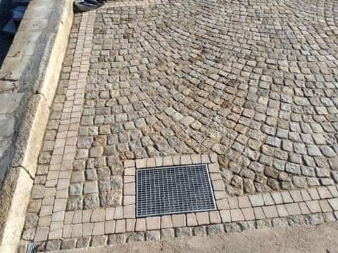 Ułożona nawierzchnia z kostki granitowej w kształcie wachlarza, obrzeża z mniejszej kostki, kratka ściekowa wkomponowana w powierzchnię.