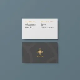 Dwie wizytówki marki Weigela: jedna biała z danymi kontaktowymi, druga szara z logo w kolorze złotym, ułożone na niebieskim tle.