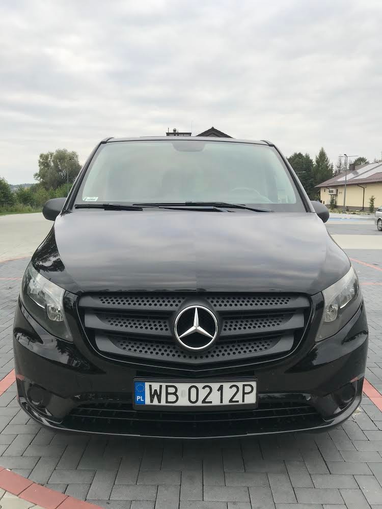 Przód czarnego Mercedesa Vito 116 z 2016 roku, wersja Long, z widoczną tablicą rejestracyjną WB 0212P i logo Mercedesa na tle szarej kostki brukowej.