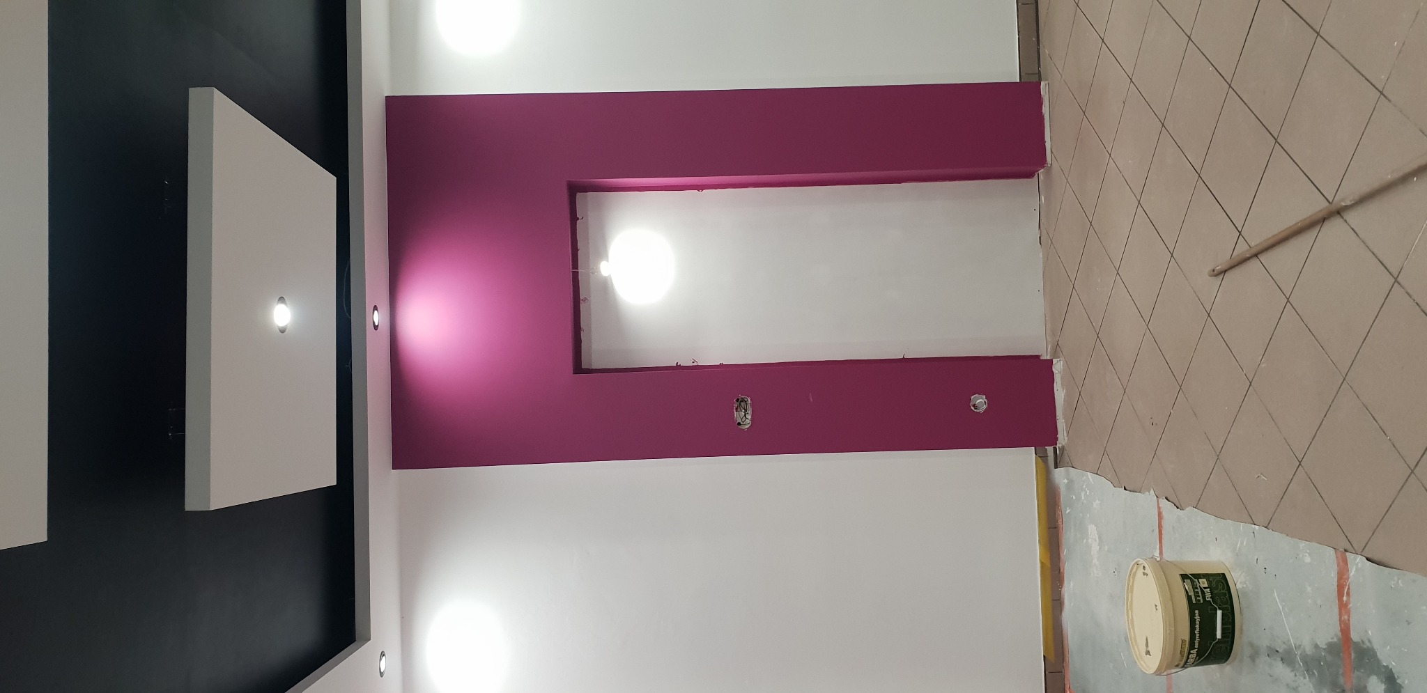 Świeżo pomalowane ściany w biurze na biało i fuksjowo, widoczne puszki z farbą i przygotowane gniazdka elektryczne.