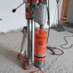 DEJV-BUD Cięcie i Wiercenie otworów w betonie, Technika Diamentowa - Wiertnica Husqvarna z wiertłem koronowym, przygotowana do wiercenia otworu w betonowej posadzce, zaznaczonego pomarańczowym kwadratem.