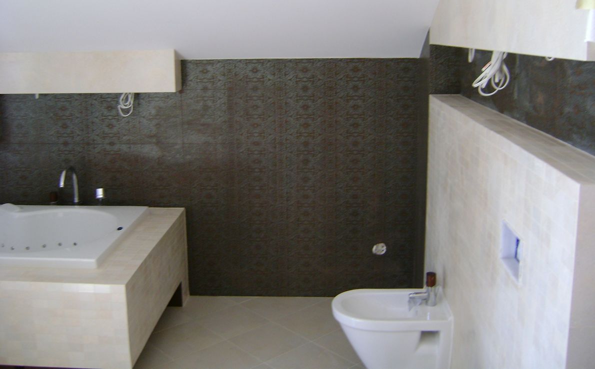 Wykończona łazienka w Kaliszu: wanna z hydromasażem obudowana mozaiką, brązowa ściana z wzorem, bidet i białe płytki z wnęką.