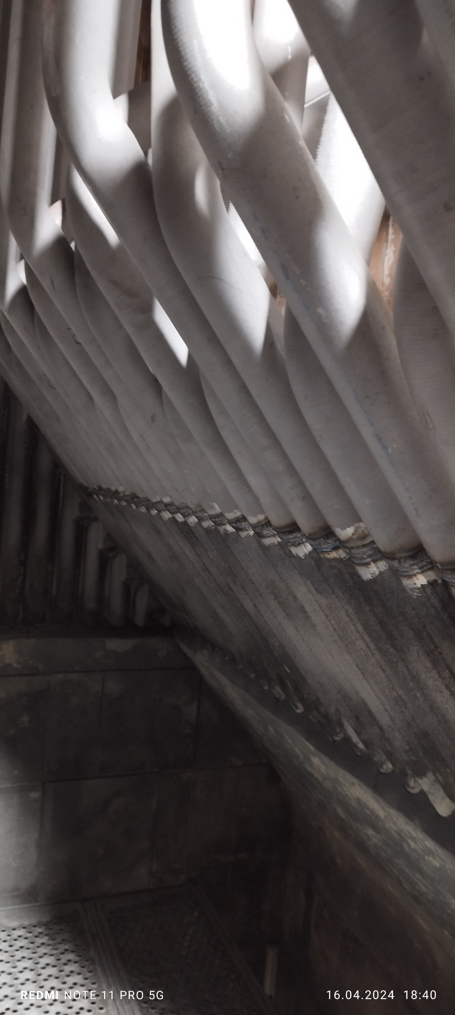 Rząd spawanych, białych rur wewnątrz kotła przemysłowego, widoczne ślady po spawaniu i zabrudzenia na ścianach.