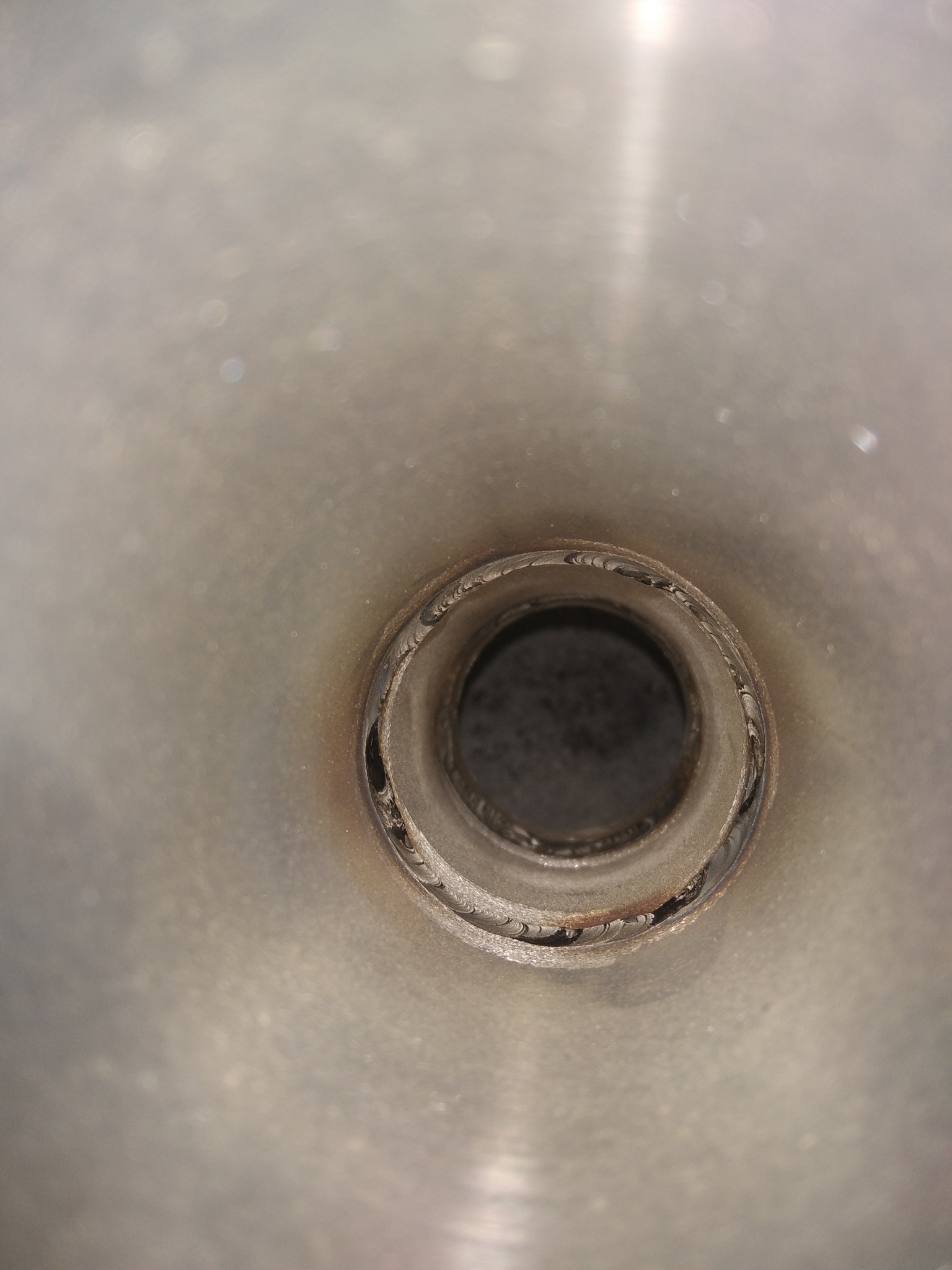 Wewnętrzny widok spawu w metalowej rurze, widoczne ślady po spawaniu.