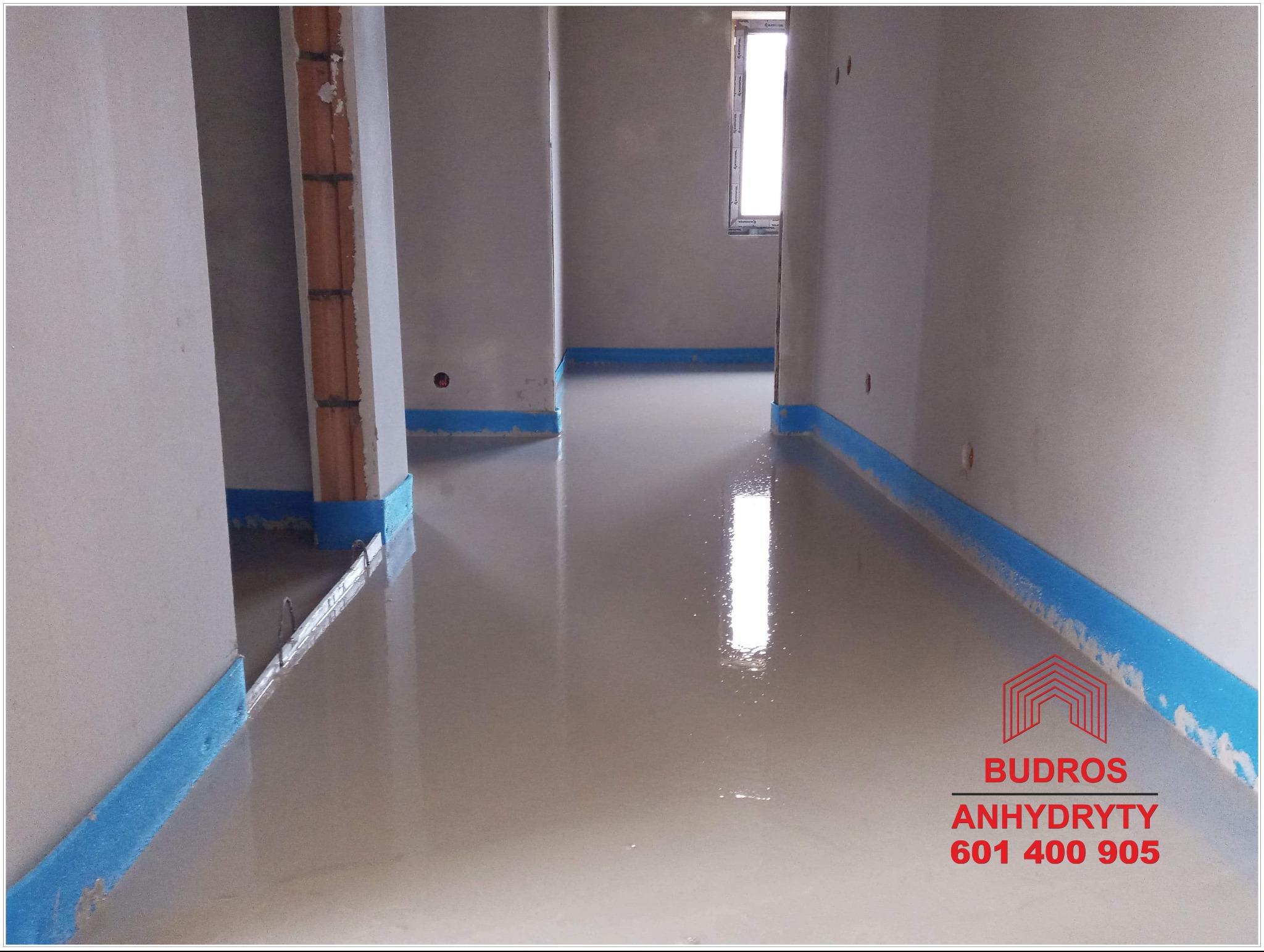 Świeżo wylana, gładka, jasnoszara posadzka w pomieszczeniu z widoczną folią ochronną przy ścianach i odbiciem światła w powierzchni.