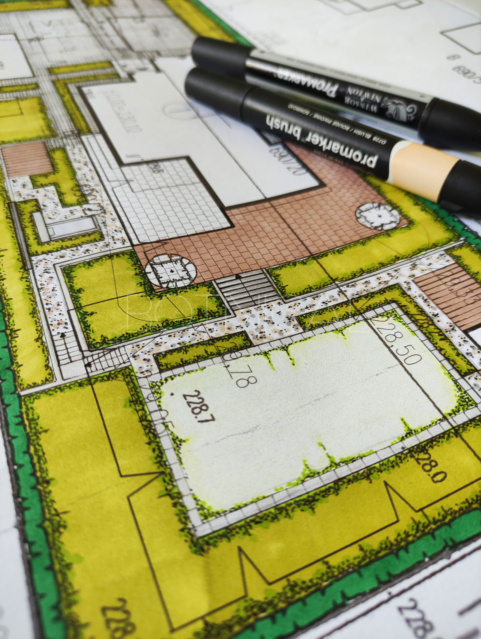 Ręcznie rysowany plan zagospodarowania terenu z zaznaczonym układem zieleni, tarasu i ścieżek, uzupełniony o dwa markery kreślarskie.