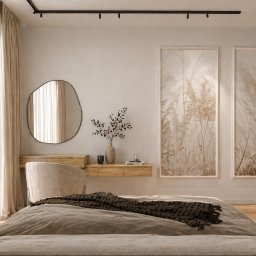 STUDIO KM architektura wnętrz Katarzyna Michoń-Kotas - Jasna sypialnia z łóżkiem, toaletką i lustrem o nieregularnym kształcie. Na ścianie grafiki w beżowych tonacjach. Minimalistyczny design, ciepłe oświetlenie.