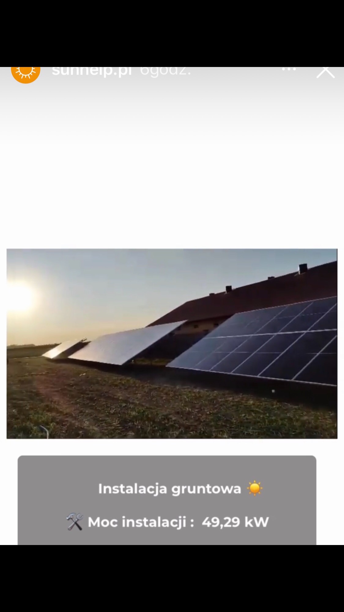 Instalacja gruntowa paneli słonecznych na tle budynku gospodarczego w promieniach zachodzącego słońca, moc instalacji 49,29 kW.