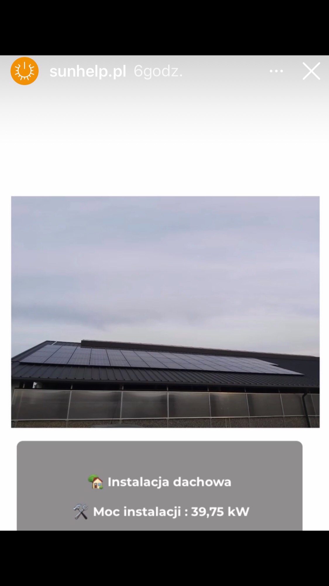 Panel słoneczny na dachu budynku gospodarczego z poliwęglanu, pochmurne niebo w tle.