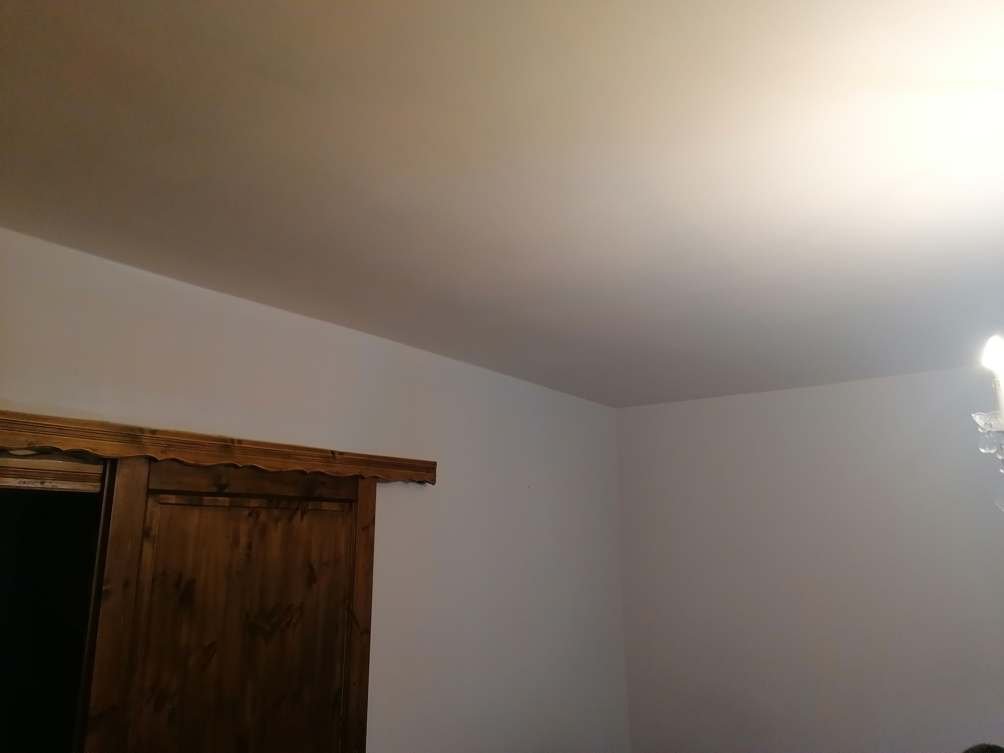 Białe ściany i sufit po odświeżeniu w mieszkaniu w Katowicach, widoczna drewniana rama drzwi przesuwnych.